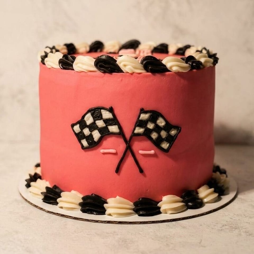 Pink cake with black and white checkered flags and matching frosting swirls.